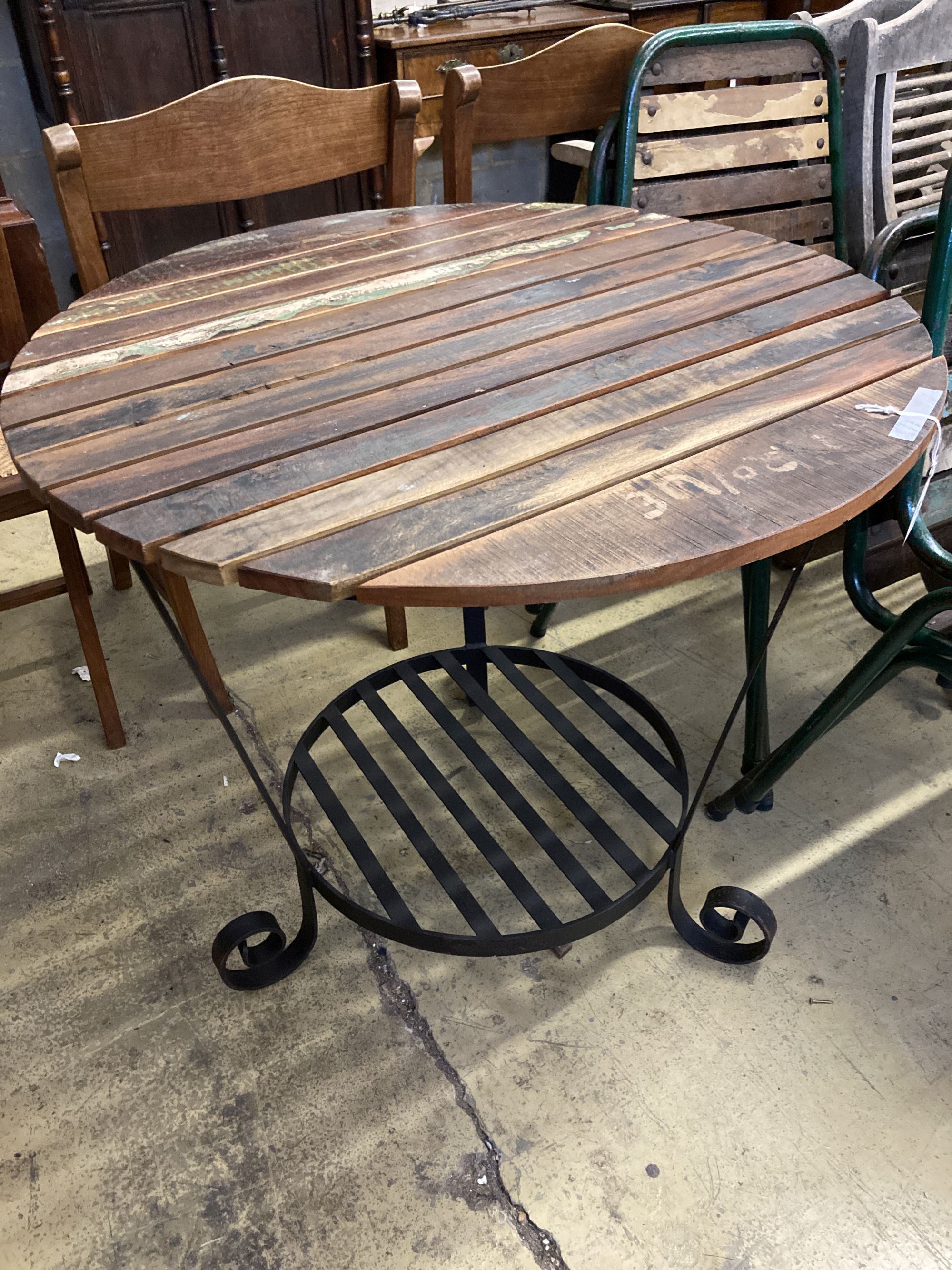 A circular slatted wood and wrought iron garden table, 85cm diameter, height 78cm together with a set of four slatted metal stacking ga